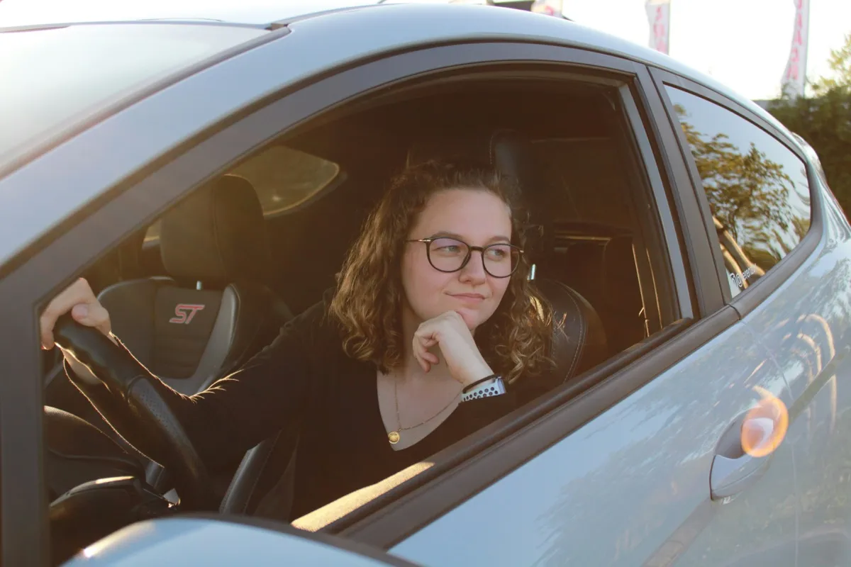 Young woman driver contemplating used car purchase, highlighting importance of pre-purchase inspections